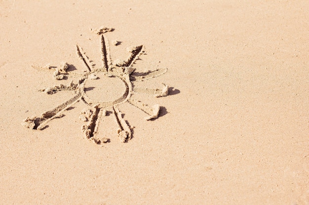 Die Sonne wird auf den Sand gemalt, Ruhe und Sommer, warme Jahreszeit und Strandsaison, Sonnenschutz