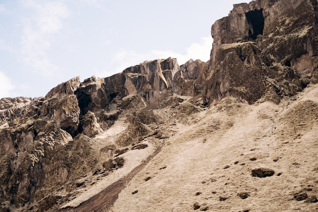 Die Spitze der felsigen Berge in Island, der Fuß des Berges, ist mit gelbem Gras bedeckt