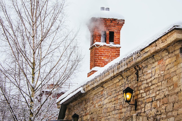 Die Spitze eines alten Steinhauses im Winter und Rauch aus dem Schornstein