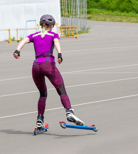 Die Sportlerin fährt auf den Rollskiern auf dem Asphalt