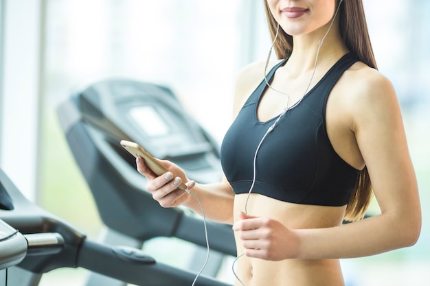 Die sportliche Frau hält ein Telefon im Fitnessclub