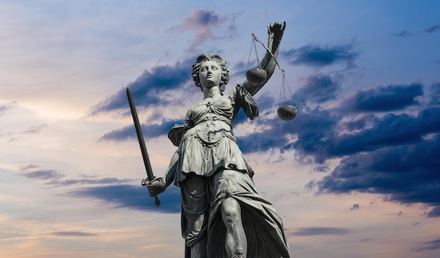 Die Statue der Gerechtigkeit - Justitia oder Iustitia gegen Sonnenunterganghimmel mit Wolken. ideal für Webseiten und Zeitschriftenlayouts