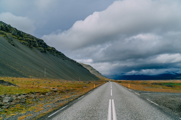 Die Straße geht über den Horizont, isländische Landschaft. Bewölkter Tag.