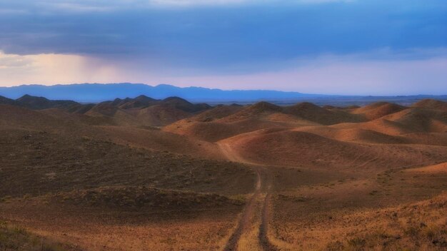 Die Straße zwischen den Schokoladenhügeln in der Abendsteppe im Herbst vor dem Hintergrund des Sonnenuntergangs Kasachstan Almaty