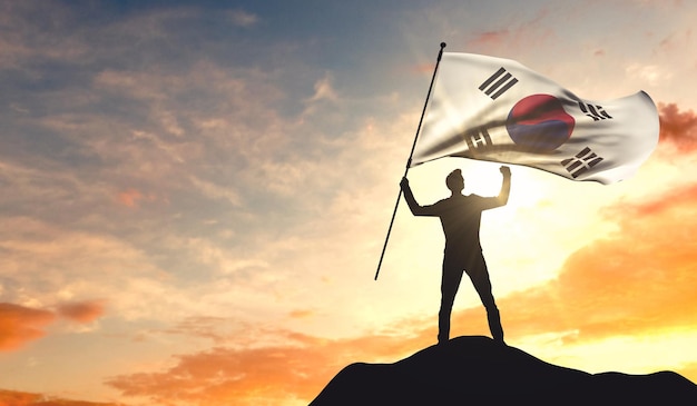 Die südkoreanische Flagge wird von einem Mann geschwenkt, der den Erfolg auf der Spitze eines Berges feiert 3D-Rendering