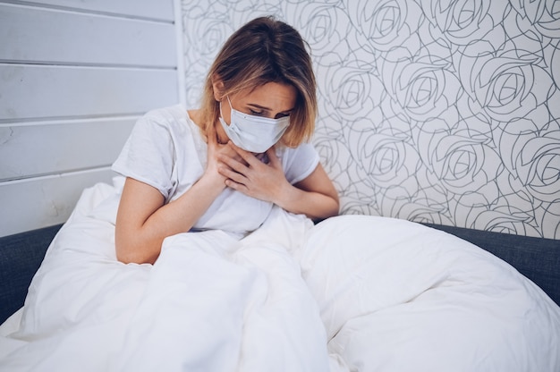 Die Symptome der Coronavirus-Krankheit (COVID-19) sind eine laufende Nase, Halsschmerzen, Husten und Fieber. Junge Frau krank von Coronavirus-Virusinfektion, die Corona-Virus verbreitet. Patient im Bett zu Hause Quarantäne liegen