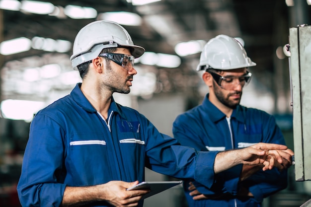 Die Teamarbeit des Ingenieurs überprüft das Bedienfeld und lehrt den neuen Mitarbeiter, die Maschine im Werk zu steuern.