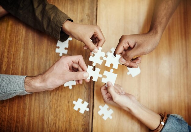 Die Teile zusammensetzen Hochwinkelaufnahme einer Gruppe nicht erkennbarer Universitätsstudenten, die beim Lernen in der Bibliothek ein Puzzle bauen