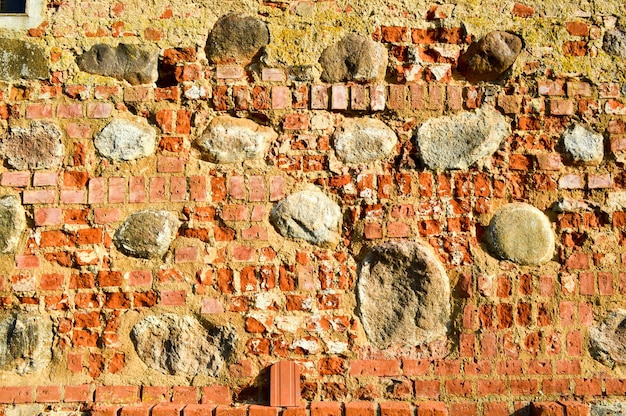 Die Textur der alten, mittelalterlichen, antiken, hart abblätternden, rissigen Ziegelmauer