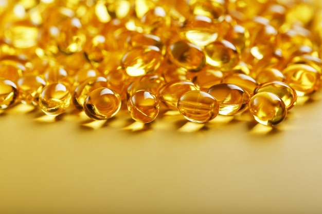 Die Textur der Kapseln in der Hülle mit flüssigem Vitamin D3 im Vollbildmodus Goldkapseln mit Nahrungsergänzungsmittel für Gelenke, Zähne und Knochen