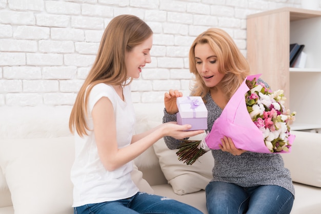 Die Tochter gibt ihrer Mutter Blumen und Geschenke.