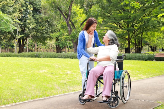 Die Tochter nahm morgens ihre betagte Mutter im Rollstuhl mit, um im Park frische Luft zu schnappen Familienkonzept Altenpflege im Rentenalter Altenpflege