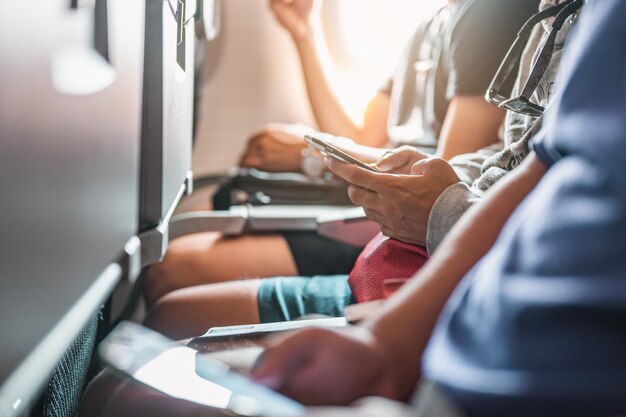 Die Touristen, die telefonieren und ein Ticket in dem Flugzeug zur Hand haben, das sich auf den Start vorbereitet. Flugzeug, Reisen, Smartphone, Flughafen, Ticket, Technologiekonzept.