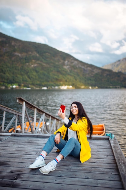 Die Touristin macht ein Foto am Telefon am See in Norwegen Junge Frau macht Selfie