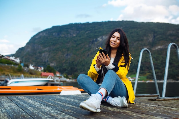 Die Touristin macht ein Foto am Telefon am See in Norwegen Junge Frau macht Selfie