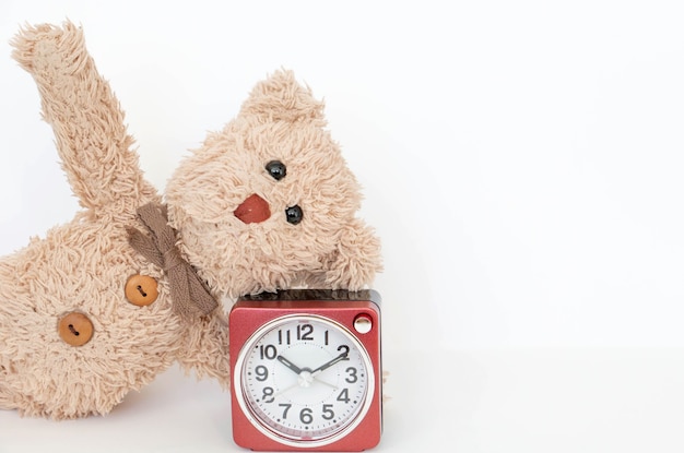 Foto die uhr und ein süßer teddybär zeigen eine einfache yoga-pose zum dehnen und stärken.