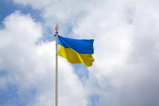 Die ukrainische Flagge auf einem Fahnenmast im Wind entwickelt sich im Hintergrund des Himmels