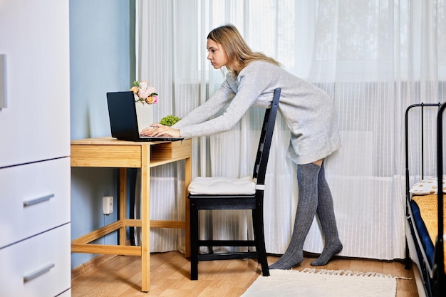 Die verführerische junge Frau, die während der Sperrung von zu Hause aus von zu Hause aus arbeitete, ging zu ihrem Laptop, um zu antworten