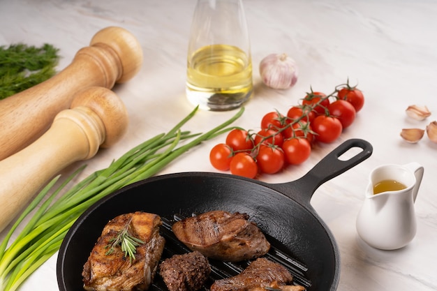 Foto die verschiedenen arten von gebratenem steak in der pfanne nahaufnahme die verschiedenen arten von gebratenem fleisch gemüse kräuter gewürze öl tomaten knoblauch pfeffer salz marmor hintergrund hochwertiges foto