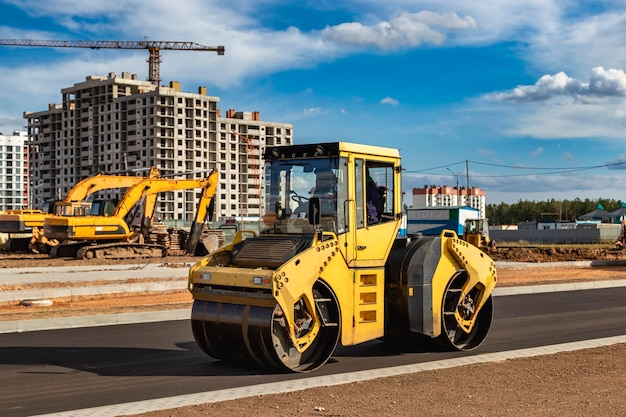 Die Vibrationswalze legt Asphalt auf einer im Bau befindlichen neuen Straße. Nahaufnahme der Arbeit von Straßenmaschinen. Bauarbeiten zum Bau von Stadtautobahnen.