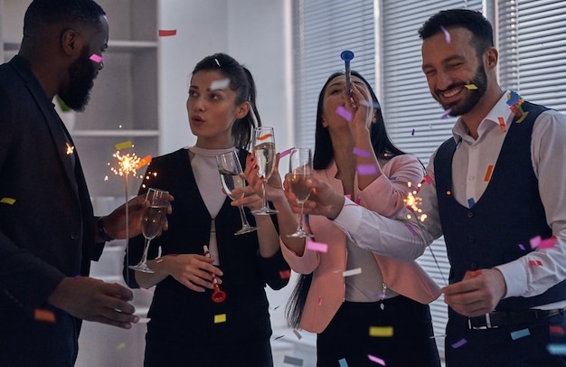 Foto die vier geschäftsleute bei einer büroparty mit champagner und konfetti