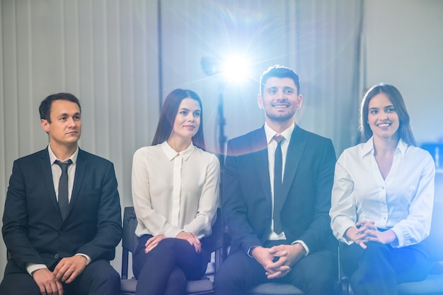 Die vier Geschäftsleute sitzen vor dem Hintergrund eines hellen Projektors