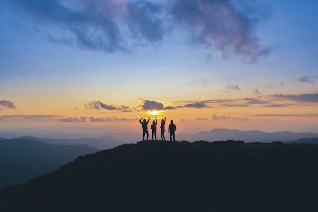 Die vier Leute, die auf dem schönen Berg auf dem Sonnenunterganghintergrund stehen