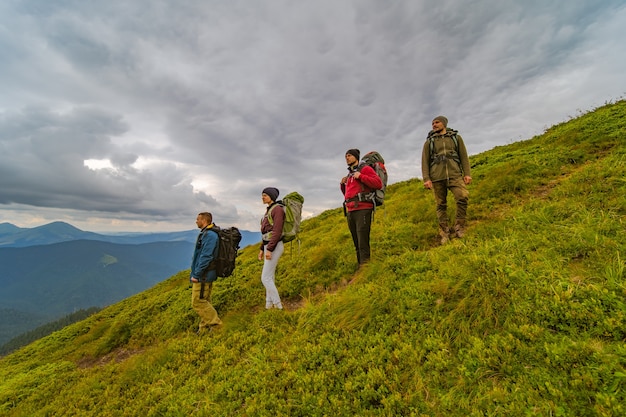 Die vier Leute mit Rucksäcken stehen auf dem grünen Berg