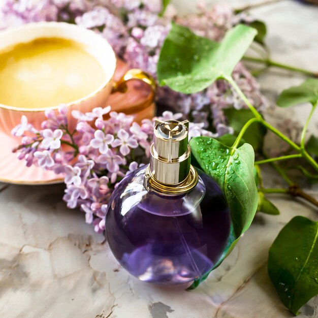 Die violette Flasche weiblichen Parfüms steht neben den Fliederblüten