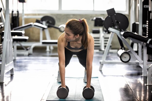 Foto die volle länge einer frau, die im fitnessstudio trainiert