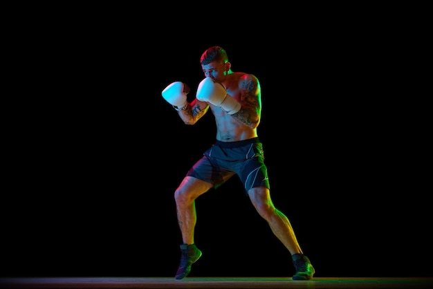 Die volle Länge eines shirtlosen jungen Mannes mit muskulösem, starkem Körper Boxer im Bewegungstraining isoliert über