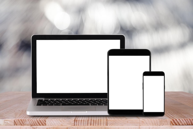 Die Vorderansicht des Laptop-Tablet-PC-Smartphones befindet sich auf dem Arbeitstisch mit Bokeh-Hintergrund