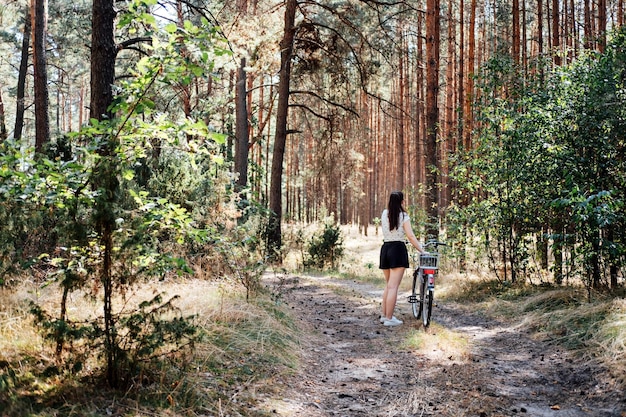 Die Vorteile des Radfahrens für die psychische Gesundheit reduzieren Ängste. Radfahren im Wald. Fahrradwege im Wald. Alleinstehende Frau fährt an sonnigen Tagen Fahrrad im Kiefernwald