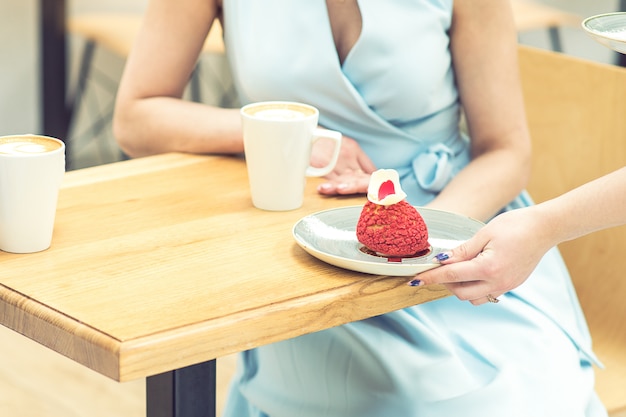 Die weibliche Hand, die ein Stück Kuchen auf den Tisch legt