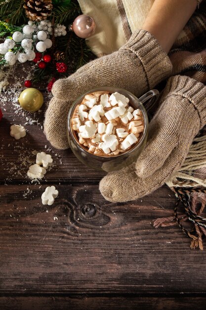 Die weiblichen Hände Fäustlinge Weihnachtsgeschenke und heißer Kakao mit Marshmallows Textfreiraum