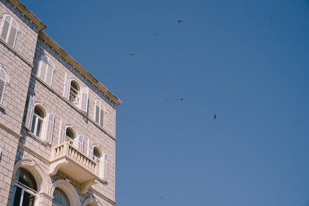 Die weiße Fassade des Gebäudes mit Bogenfenstern und Säulen auf den Balkonen gegen das Blau