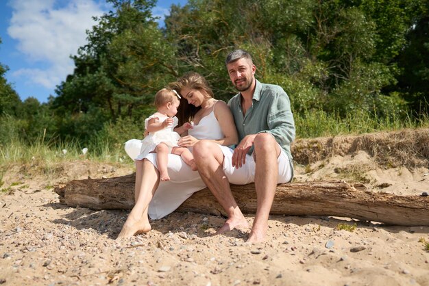 Foto die weiße kaukasische familie entspannt sich am strand mit ihrem einjährigen baby.