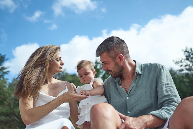 Die weiße kaukasische Familie entspannt sich mit ihrem einjährigen Baby auf dem Strand