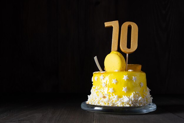 Die Zahl Siebzig auf einem gelben Kuchen zum Jubiläum oder Geburtstag in einem dunklen Schlüssel