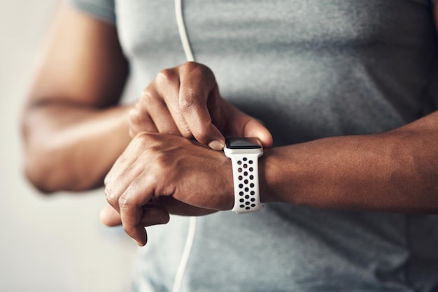 Die Zahlen belegen, dass Sie Fortschritte machen Nahaufnahme eines nicht wiederzuerkennenden Mannes, der seine Armbanduhr überprüft, während er zu Hause trainiert