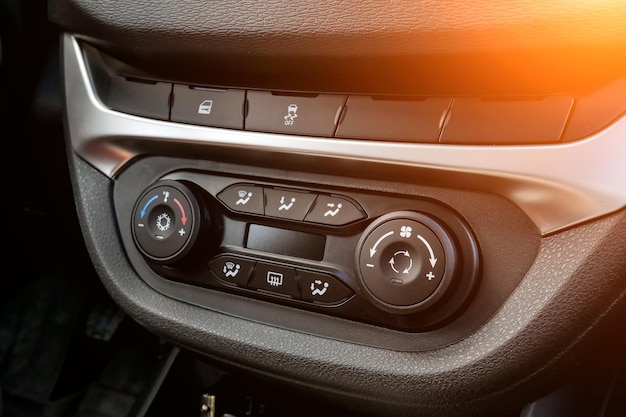 Die zentrale Bedienkonsole auf der Verkleidung im Innenraum des Autos, Nahaufnahme mit Klimaanlage und Audiosystem und einem Loch für die CD und den Notrufknopf in Grau und Schwarz