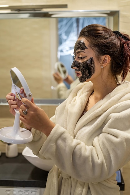 Die zerbrechliche Dame legt eine heilende schwarze Maske auf ihr Gesicht, um ihre Haut zu verbessern