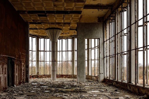 Die zerstörte halle eines alten gebäudes mit breiten fenstern. glasscherben auf dem boden.