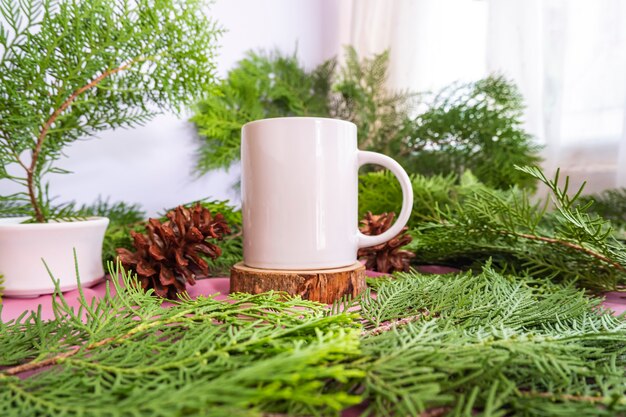 Die Zusammensetzung zeigt das Produkt. weiße Tasse auf altem Rundholz mit Tannenblattdekoration. Ideen für die Produktpräsentation im Sommer