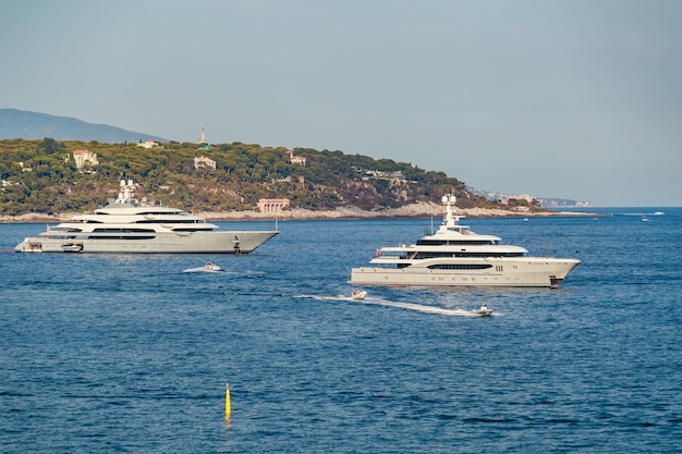 Die zwei riesigen Mega-Yachten sind an sonnigen Tagen im Meer festgemacht, die verchromte Handlauf-Sonnenreflexion an