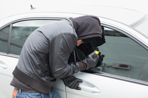 Dieb, der mit Schraubenzieher in Auto einbricht