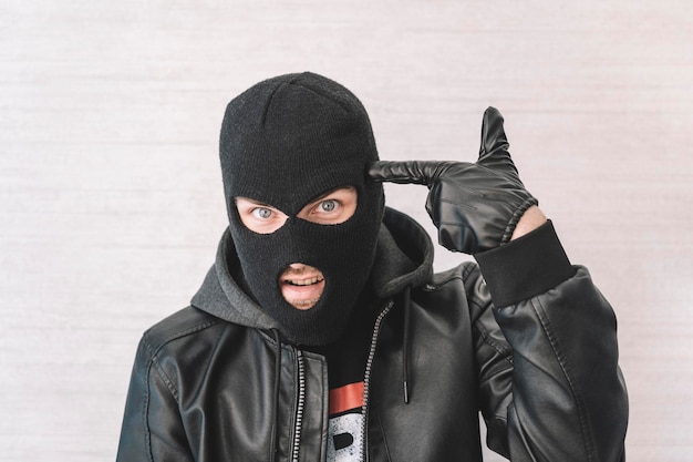 Foto dieb in einer schwarzen jacke ein mann in einer schwarzen sturmhaube mit einem bösen gesichtsausdruck ein aggressiver bandit auf weißem hintergrund das konzept von verbrechen oder diebstahl