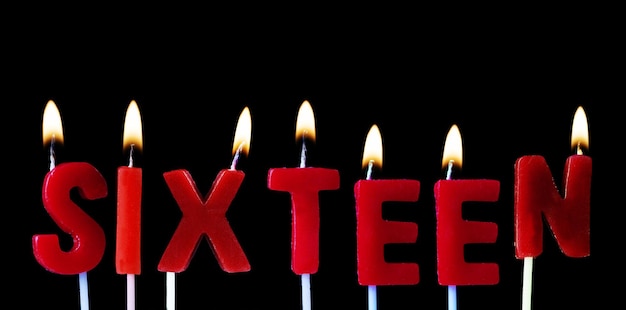 Foto dieciséis escritos en velas de cumpleaños rojas contra un fondo negro