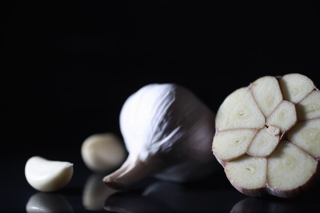 Diente de ajo fresco sobre fondo negro. El ajo es rico en vitaminas, primavera útil, buenas especias. Ajo en rodajas sobre un fondo oscuro. Ajo crudo en rodajas.