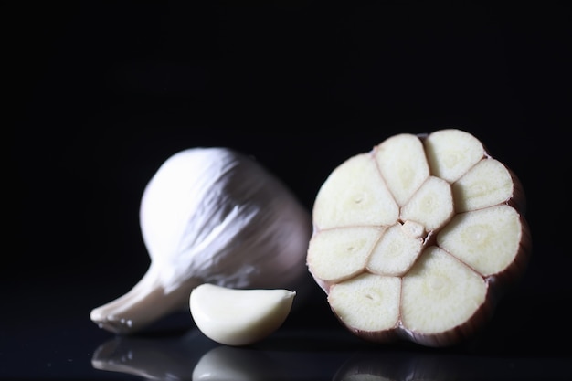 Diente de ajo fresco sobre fondo negro. El ajo es rico en vitaminas, primavera útil, buenas especias. Ajo en rodajas sobre un fondo oscuro. Ajo crudo en rodajas.